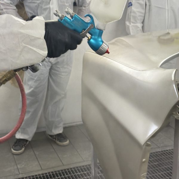 Demostración de técnicas de pintura automotriz realizadas en cabina especializada.